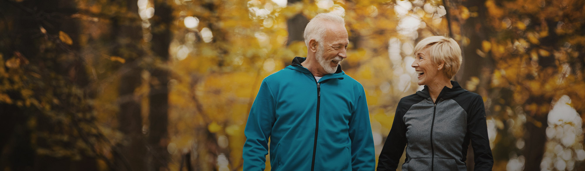 Two People Smiling While Walking in Woods