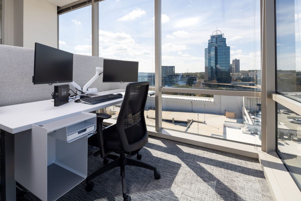 corner cubicle with desk and equipment, looking out at the city