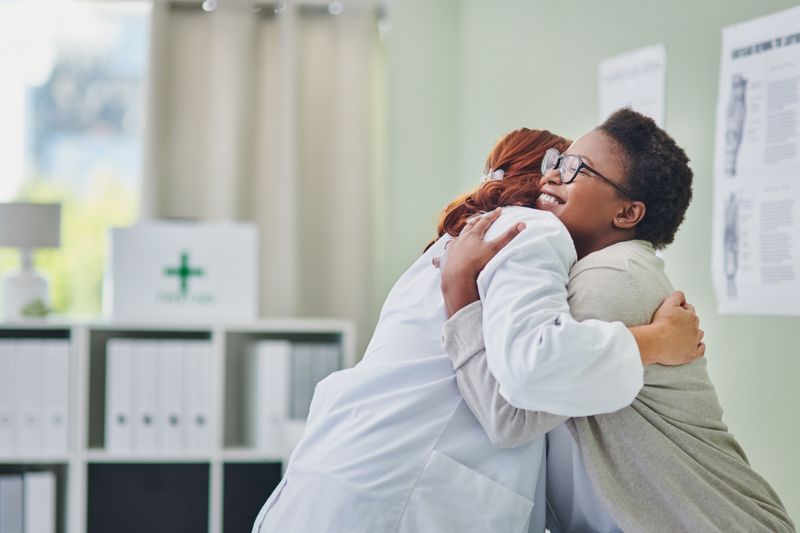 Two women embracing for a hug in a medical setting.