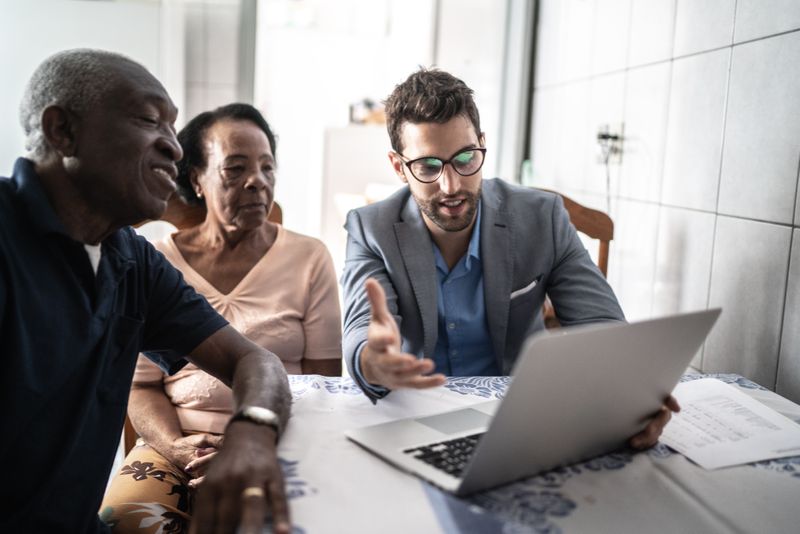 A man reviewing types of financial benefits with an older couple.