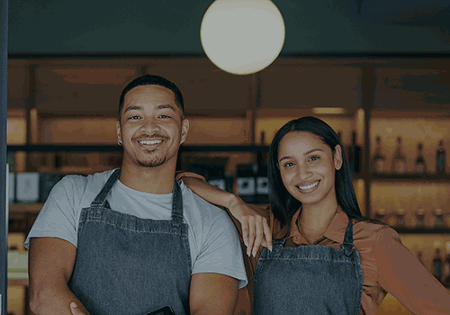 smiling man and woman posing in front of storefront windows
