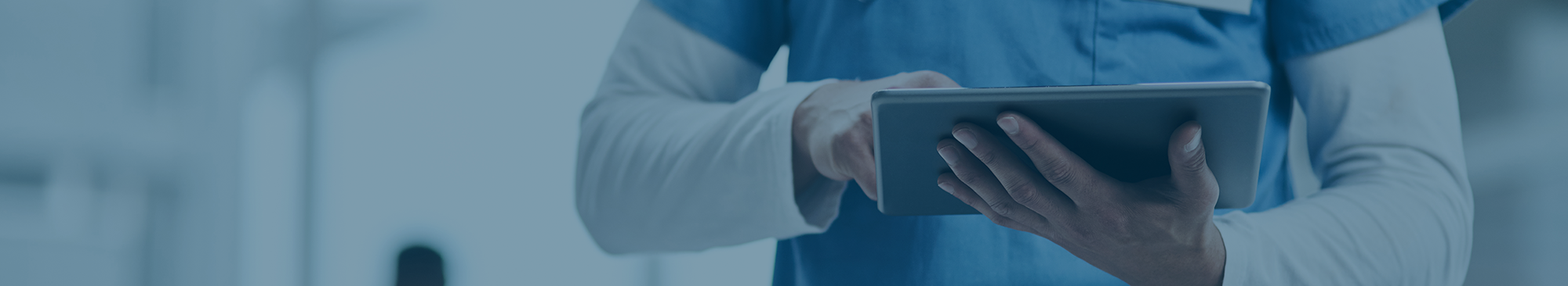 person in scrubs holding and using tablet