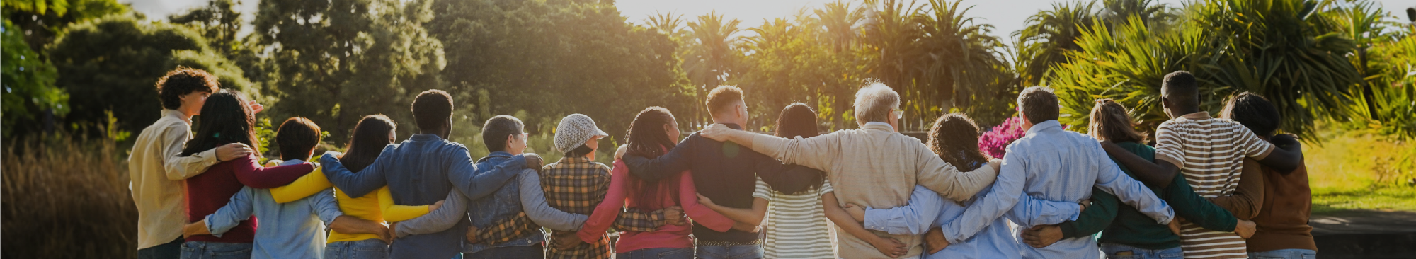 diverse group of people standing in a line with arms around each other, facing away from camera