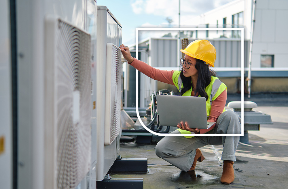 woman in high visibility vest and hard hat assessing building hvac fan