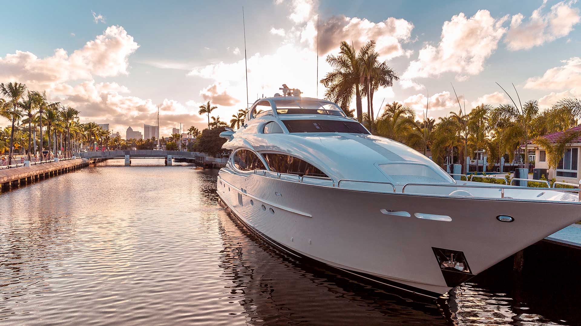 view of moored yacht from front with palm trees and skyscrapers in background