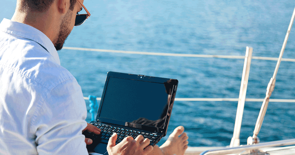 man on boat deck sitting and using laptop