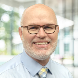 Headshot of Erik Western, a fair-skinned bald man with glasses