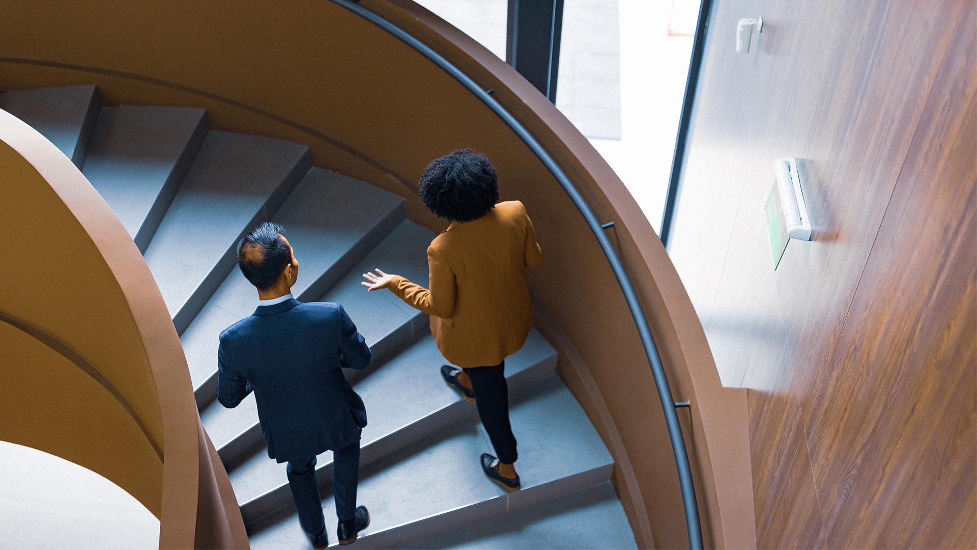 business people walking up spiral staircase