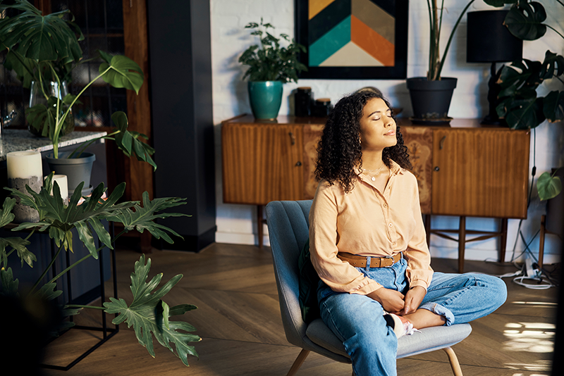 a woman sitting on a chair, with eyes closed and head up