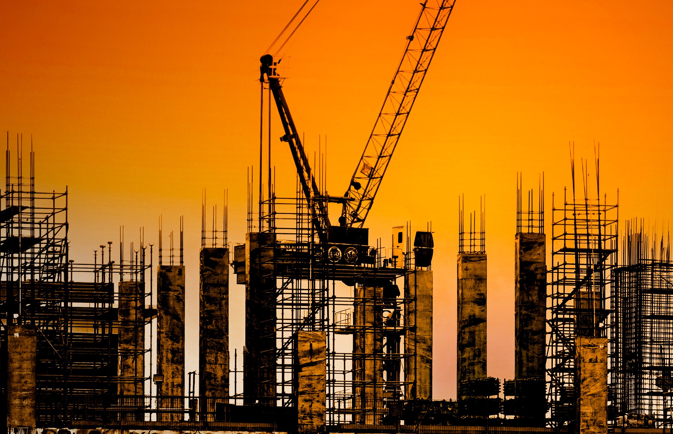 construction crane with pillars against orange sky