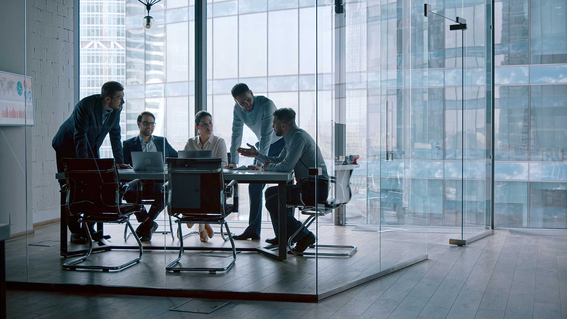 team working in glass-encased meeting room with table