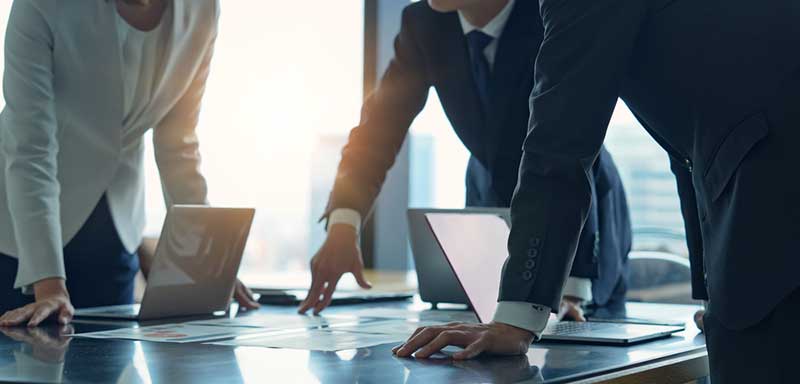 people reviewing item on glass meeting table