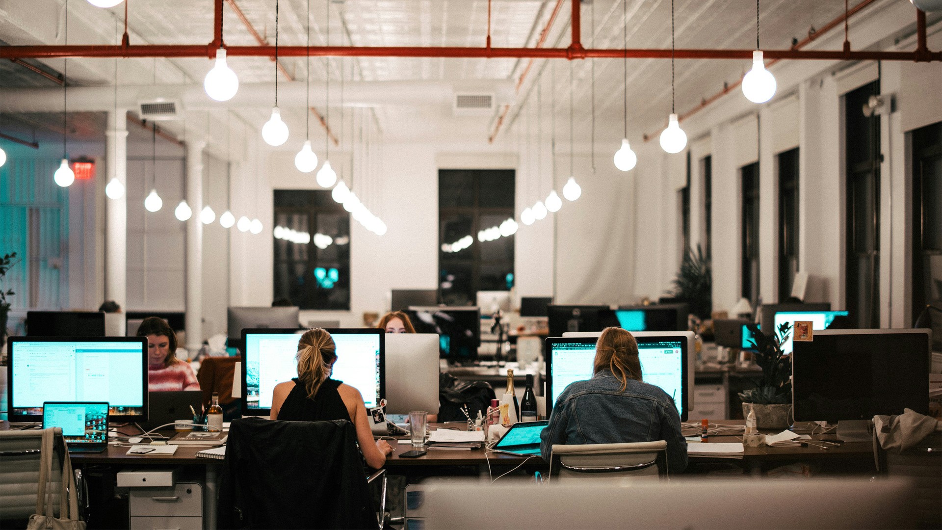 open office with people at desks and large monitors