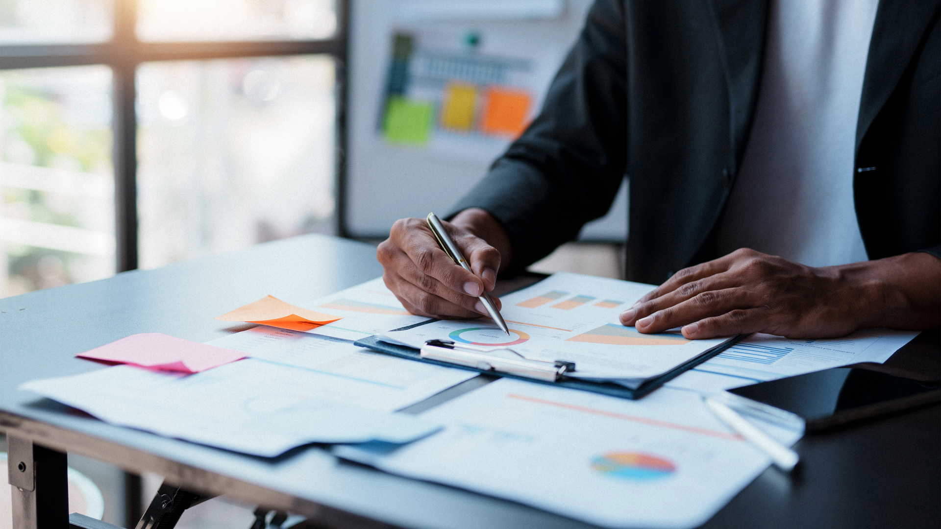business professional pointing to pie graph on page with pen